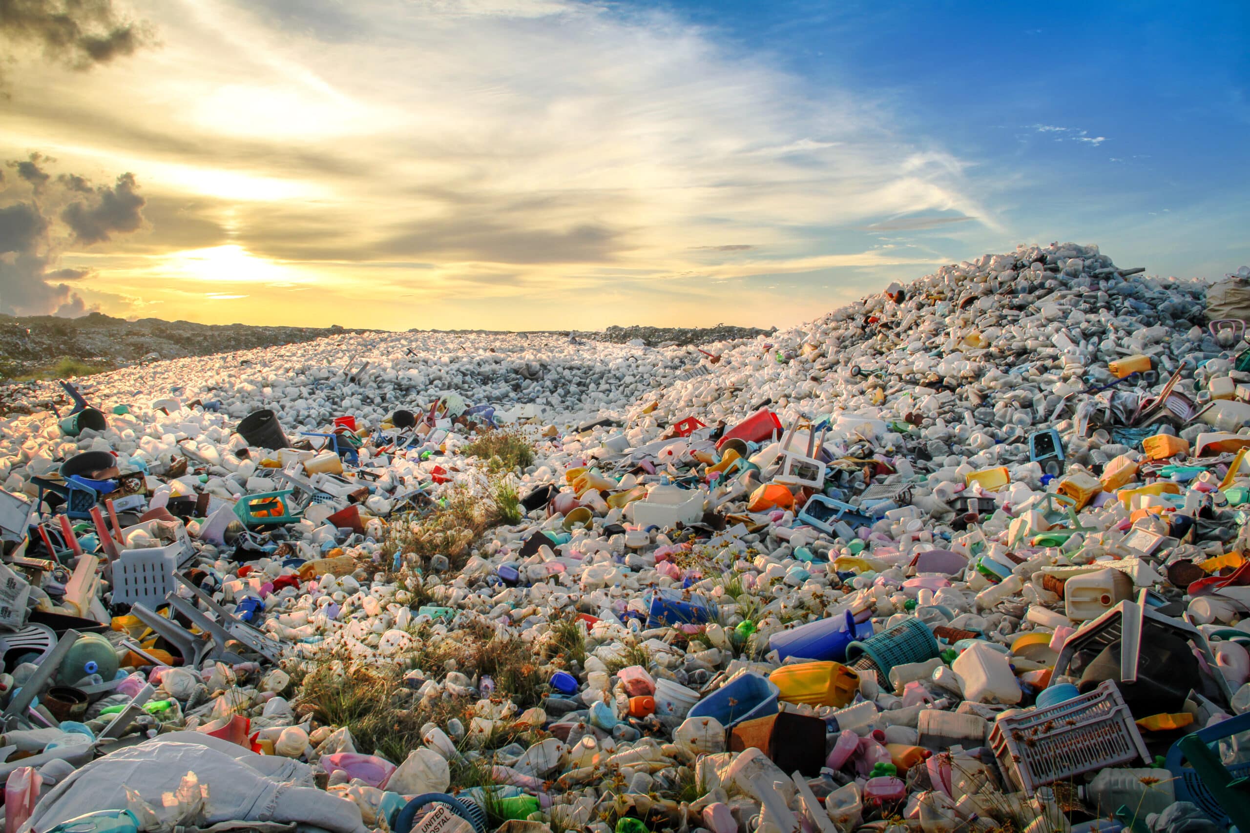 A vast landfill stretching to the horizon, densely covered with discarded single-use plastic water bottles